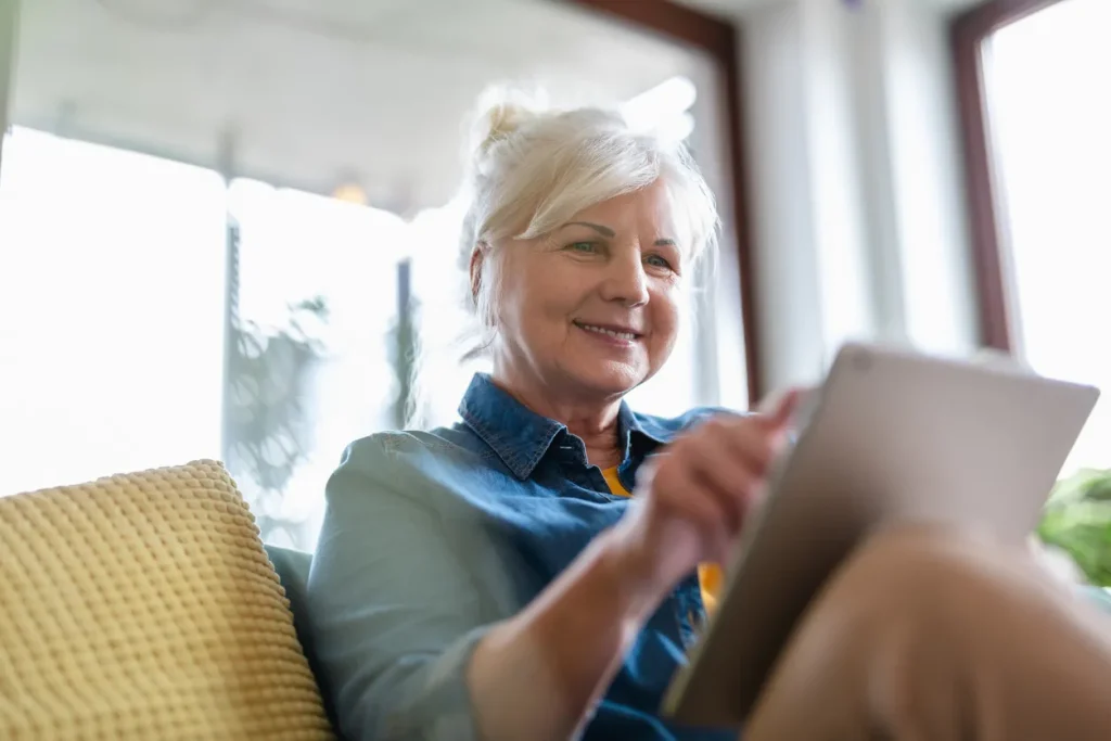 An older woman using an iPad to fill out a contact us form, demonstrating ease of access and user-friendly digital communication for all ages.