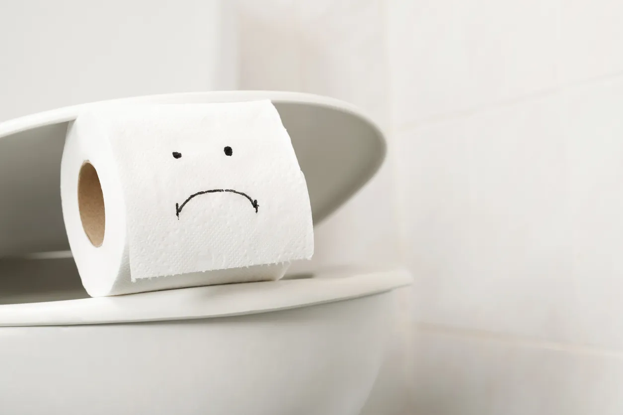 A roll of toilet paper with a sad face placed on a toilet, symbolizing the discomfort and need for effective remedies for diarrhea.