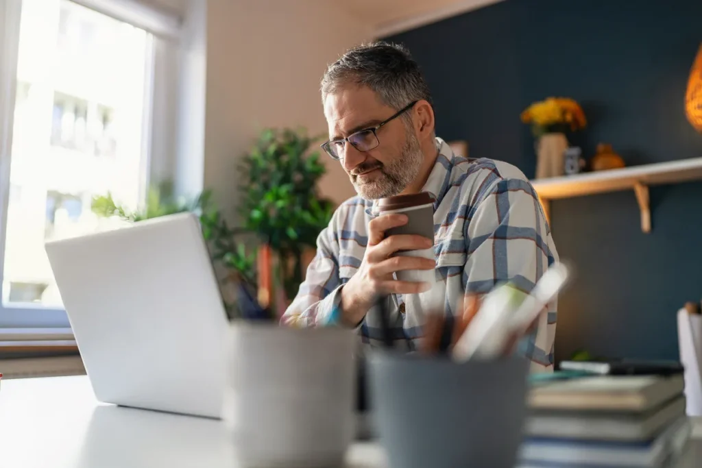 Middle-aged man drinking coffee while attending a webinar, representing the sign-up page for our webinar or newsletter.