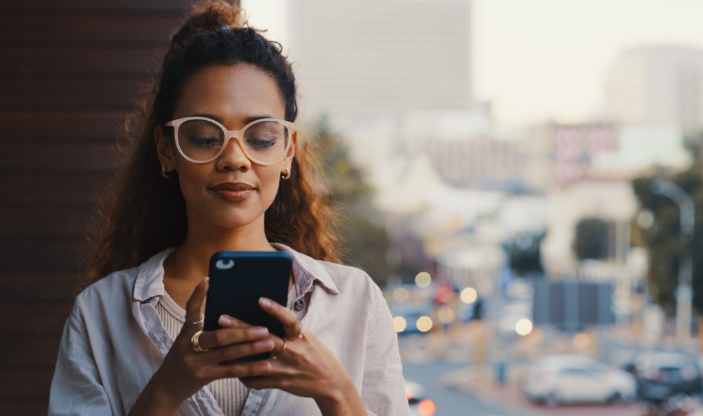 Shot of an attractive young woman receiving updates from GetReliefRX Compounded Pharmacy while standing outside on the a balcony