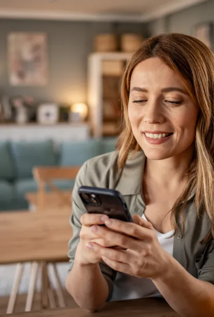 A woman smiles while using her phone to type.