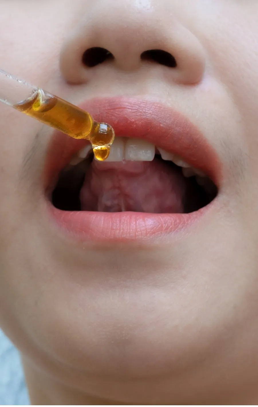 A woman takes medication from a dropper.