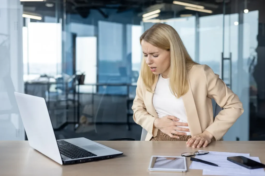 A woman at work grabbing her stomach in pain, illustrating the discomfort associated with abdominal pain and diarrhea