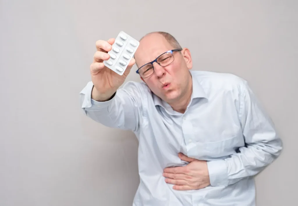 Stop Diarrhea here is an image of a man on the toilet suffering from diarrhea holding pills. Illustrating the need for an Anti-Diarrheal Treatment