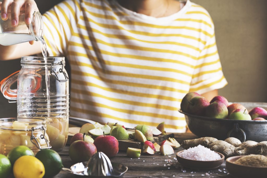 A person prepares a homemade apple cider vinegar drink, showcasing a natural remedy for stomach cramps and diarrhea. This image highlights the use of apple cider vinegar to alleviate abdominal pain and diarrhea and address gastrointestinal cramps and loose stools.