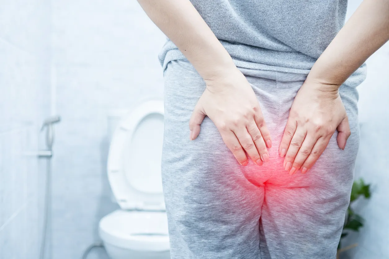 A person in the bathroom clutching their lower back, clearly in discomfort, suffering from chronic intractable diarrhea, a condition associated with increased mucosal mast cells and known as mastocytic enterocolitis. The image reflects the struggle and pain of living with this persistent digestive issue.