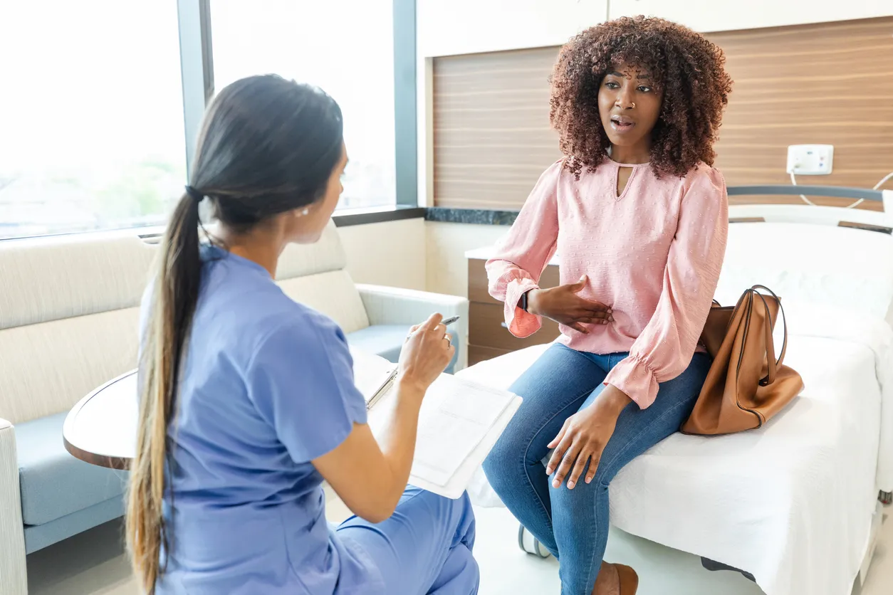 A woman discussing her stomach pain with a healthcare provider, illustrating the symptoms of digestive distress, including stomach cramps and diarrhea.